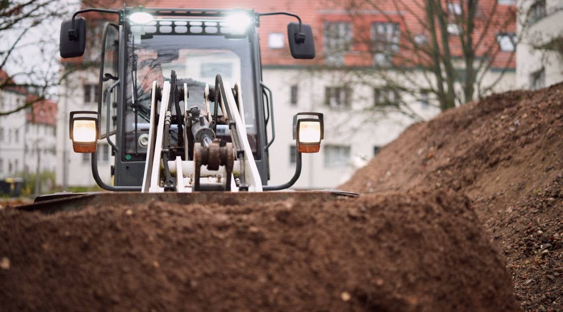 Eine Person bewegt Erde mit einem Bagger.