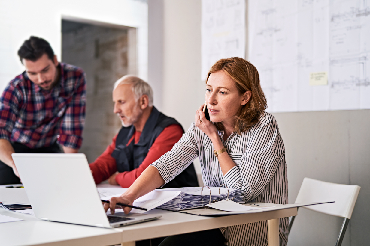 Mitarbeiterin für Grünflächenplanung tippend im Büro am Telefon. Mitarbeiterin für Grünflächenplanung tippend im Büro am Telefon.