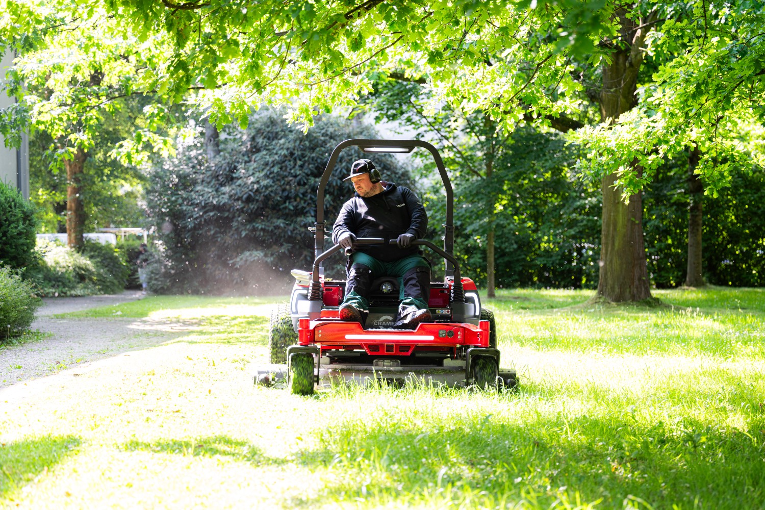 Mitarbeiter auf einem Aufsitzmäher bei der Außenanlagenpflege. Mitarbeiter auf einem Aufsitzmäher bei der Außenanlagenpflege.