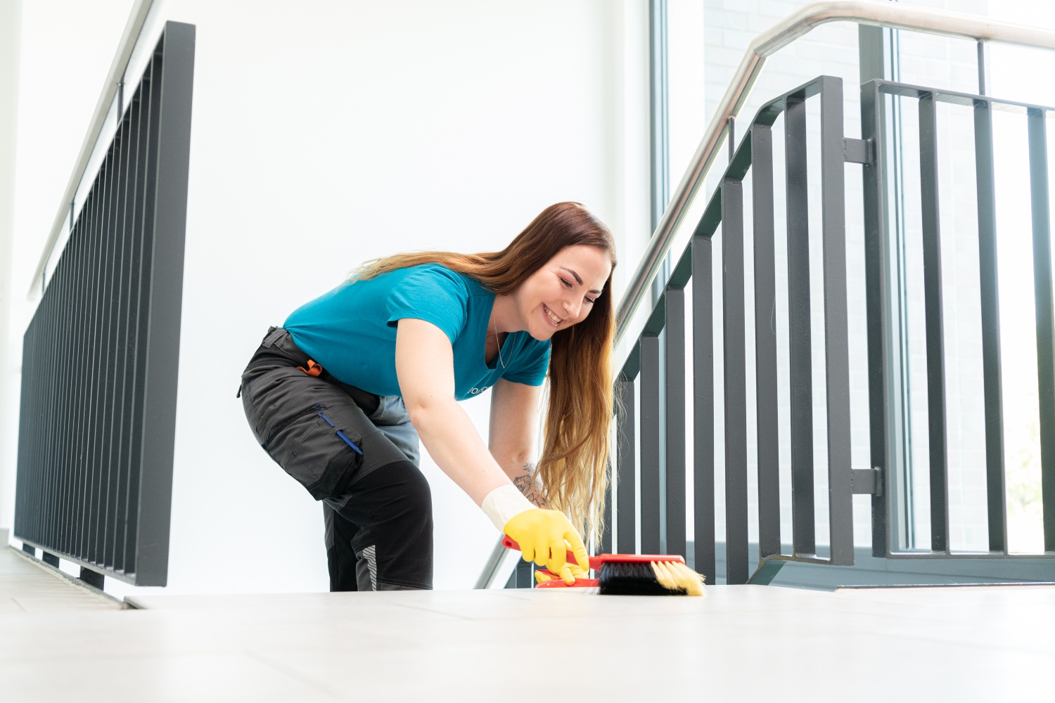 Vonovia Mitarbeiterin mit Handfeger und Kehrschaufel bei der Treppnehausreinigung. Vonovia Mitarbeiterin mit Handfeger und Kehrschaufel bei der Treppnehausreinigung.