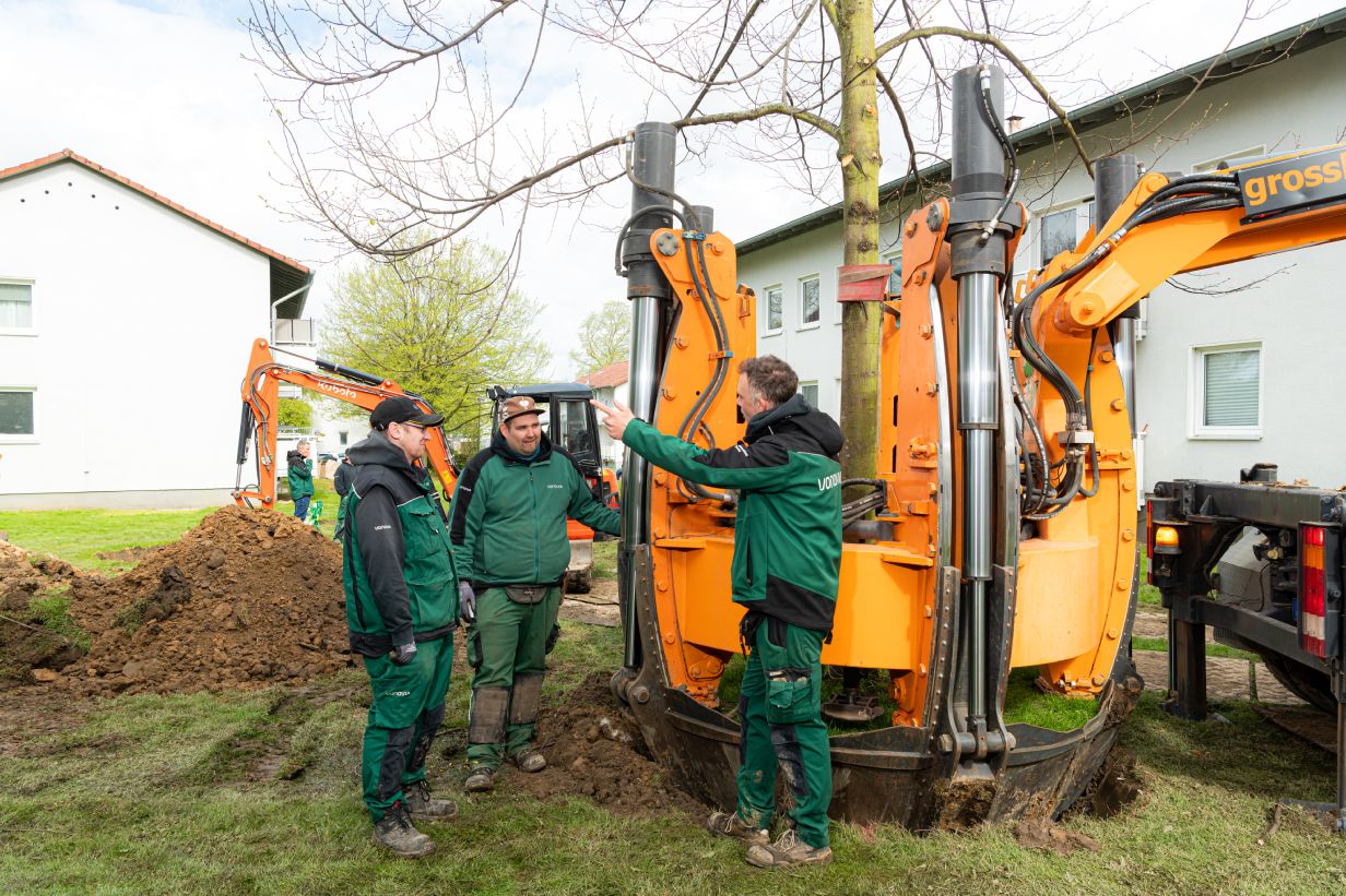 Team aus dem Galabau mit Rundspatenmaschine bei der Verpflanzung eines großen Baumes.